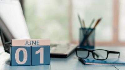June calendar on desk next to glasses and laptop