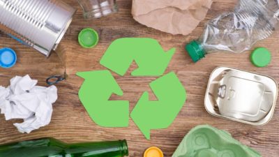 Rubbish and waste around a green recycling logo.