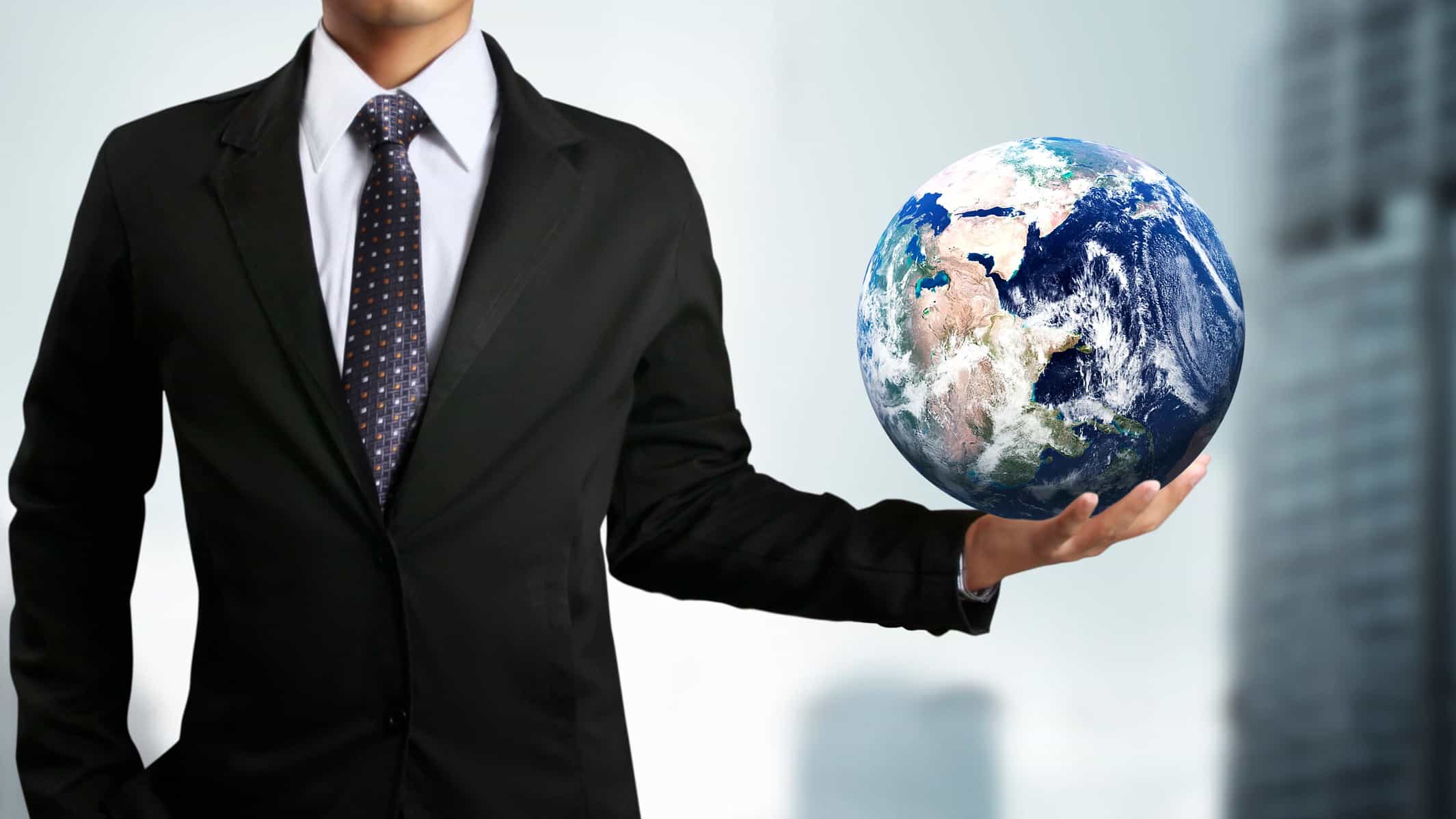A businessman holding a world globe in one hand, representing global investment.
