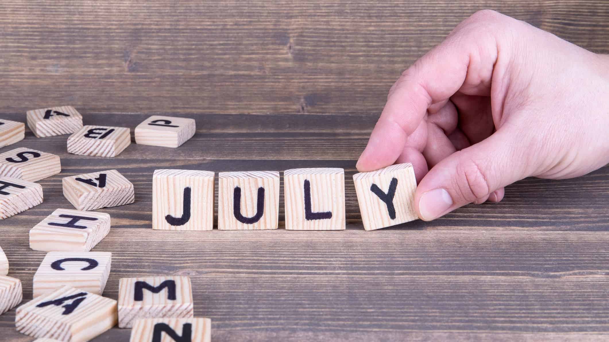 hand selecting wooden letter tiles to spell the word july