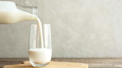 pouring glass of milk from glass milk bottle