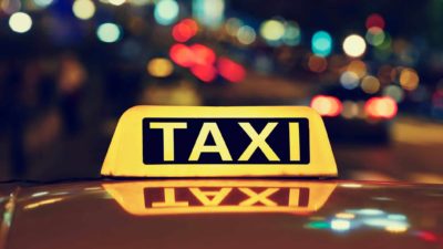 illuminated taxi sign against backdrop of city lights