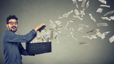 Man in grey shirt with glasses opens box with banknotes flying out to represent cash flow