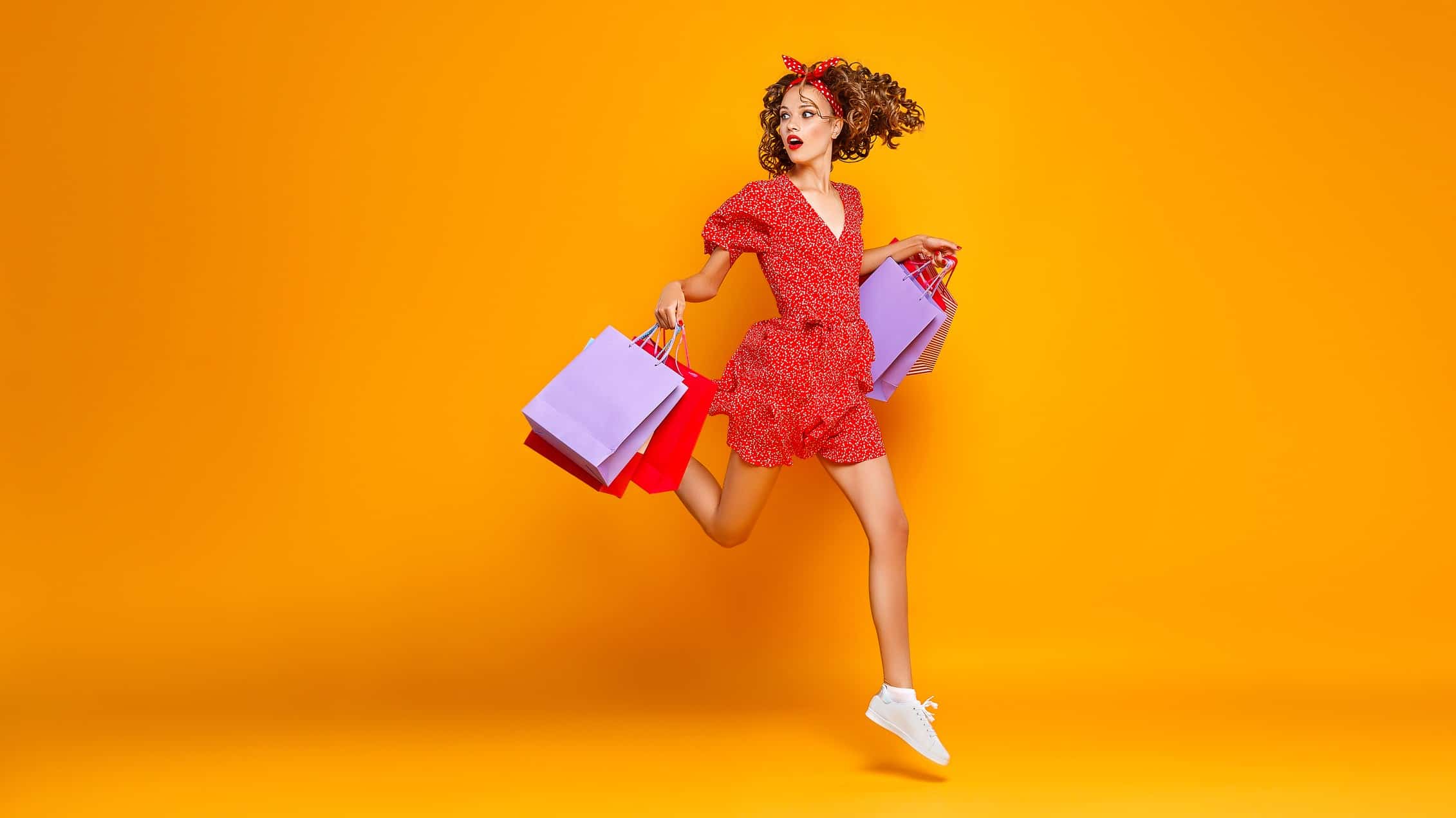 woman excitedly holding shopping bags and jumping