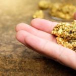 Hand holding gold nugget reflecting Newcrest Mining share price today