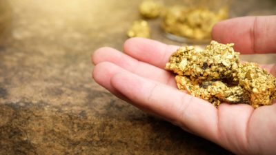 Hand holding gold nugget reflecting Newcrest Mining share price today