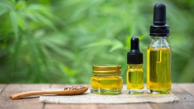 Bottles and vials of hemp oil in a row next to a spoon filled with hemp seeds representing asx cannabis shares