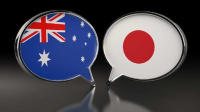 Japan and Australia flags in speech bubbles on black background
