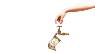 Hand turning brass tap with banknote coming out of it to represent liquidity