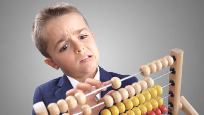 young boy in business suit holding abacus and frowning