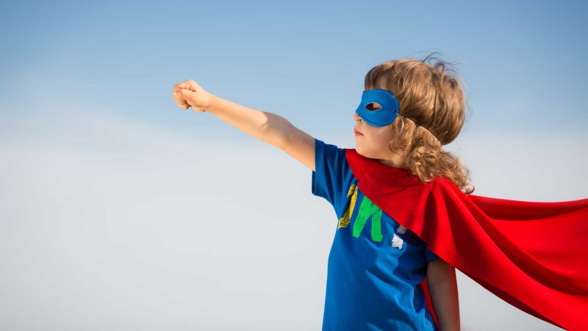child in superman outfit pointing skyward, indicating a rising share price