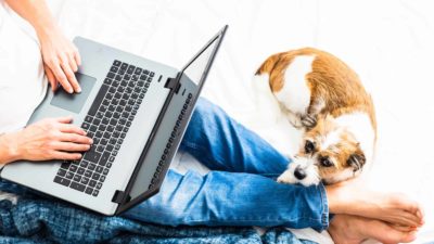 man working from home on laptop next to dog