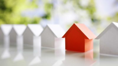 asx shares for housing boom represented by row of miniature white paper houses with one red house