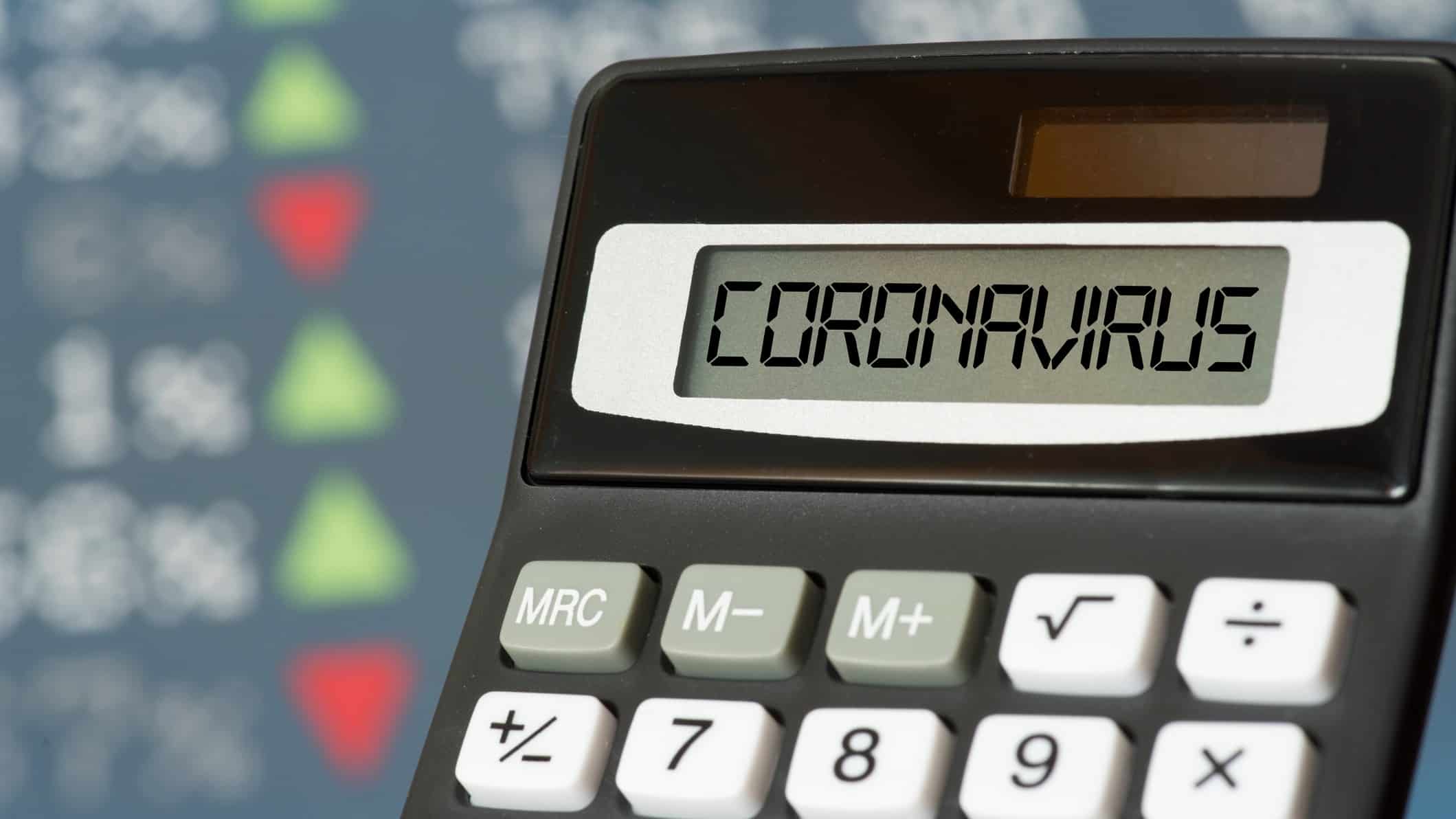 calculator spelling coronavirus against backdrop of stock market board