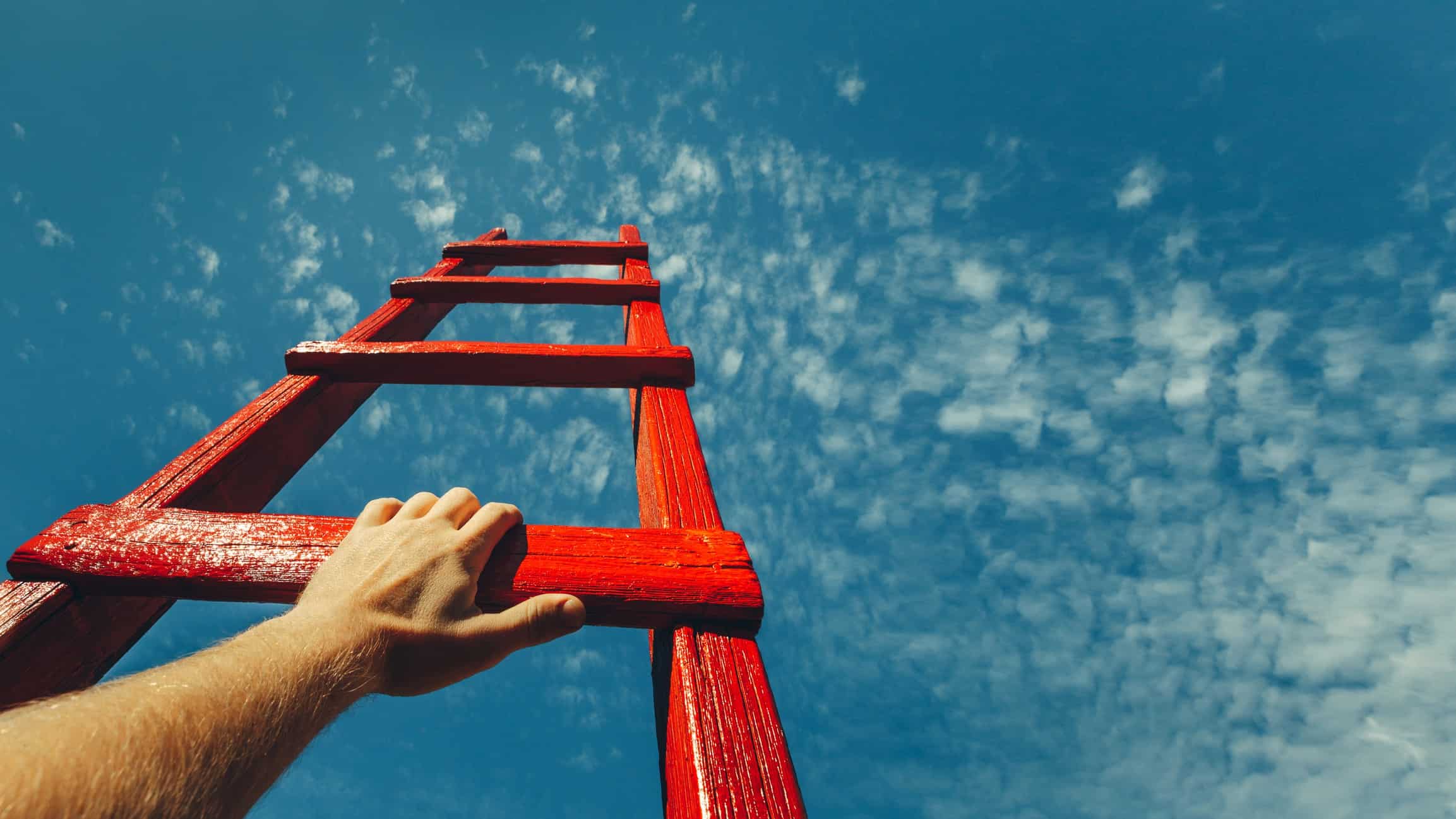 Hands grabbing for high rung on a ladder pointing to the sky