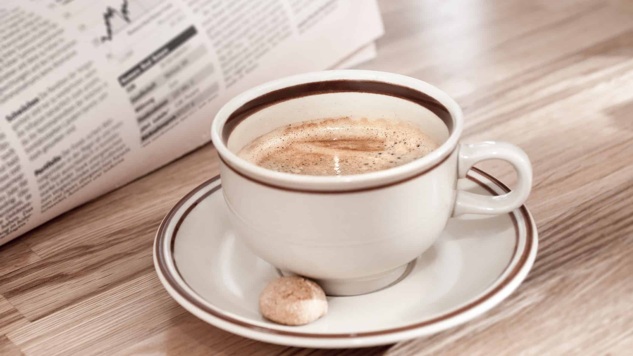 cup of coffee next to newspaper open to stock market page