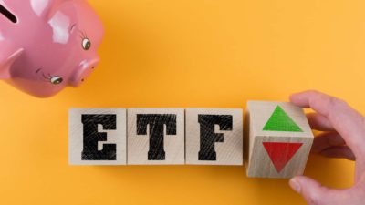 Block letters 'ETF' on yellow/orange background with pink piggy bank