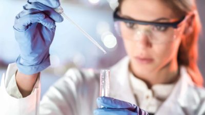 woman in lab coat conducting testing representing biotech