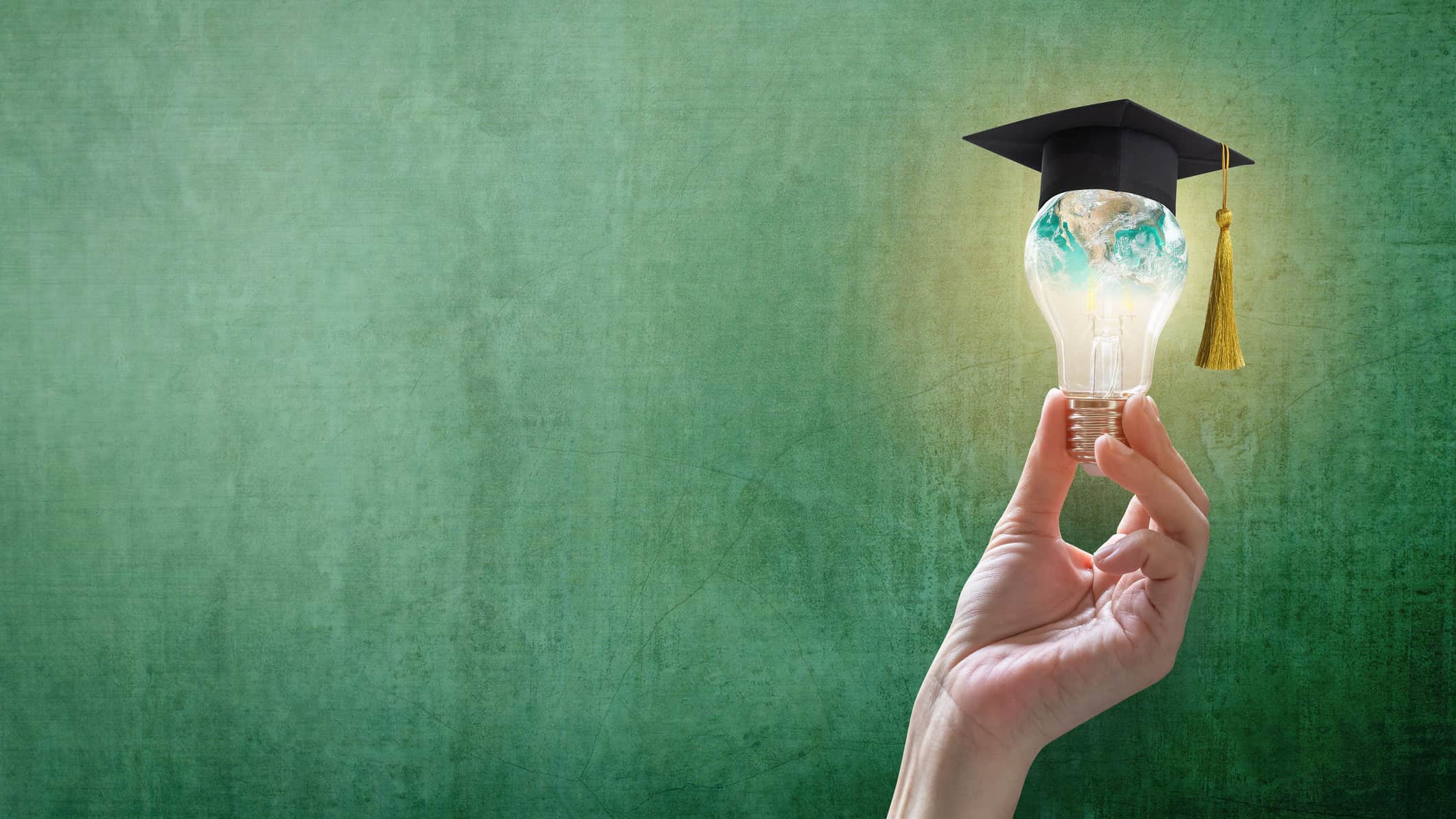 Hand holds up a lightbulb with a small graduates cap on top of it to symbolise wisdom and ideas