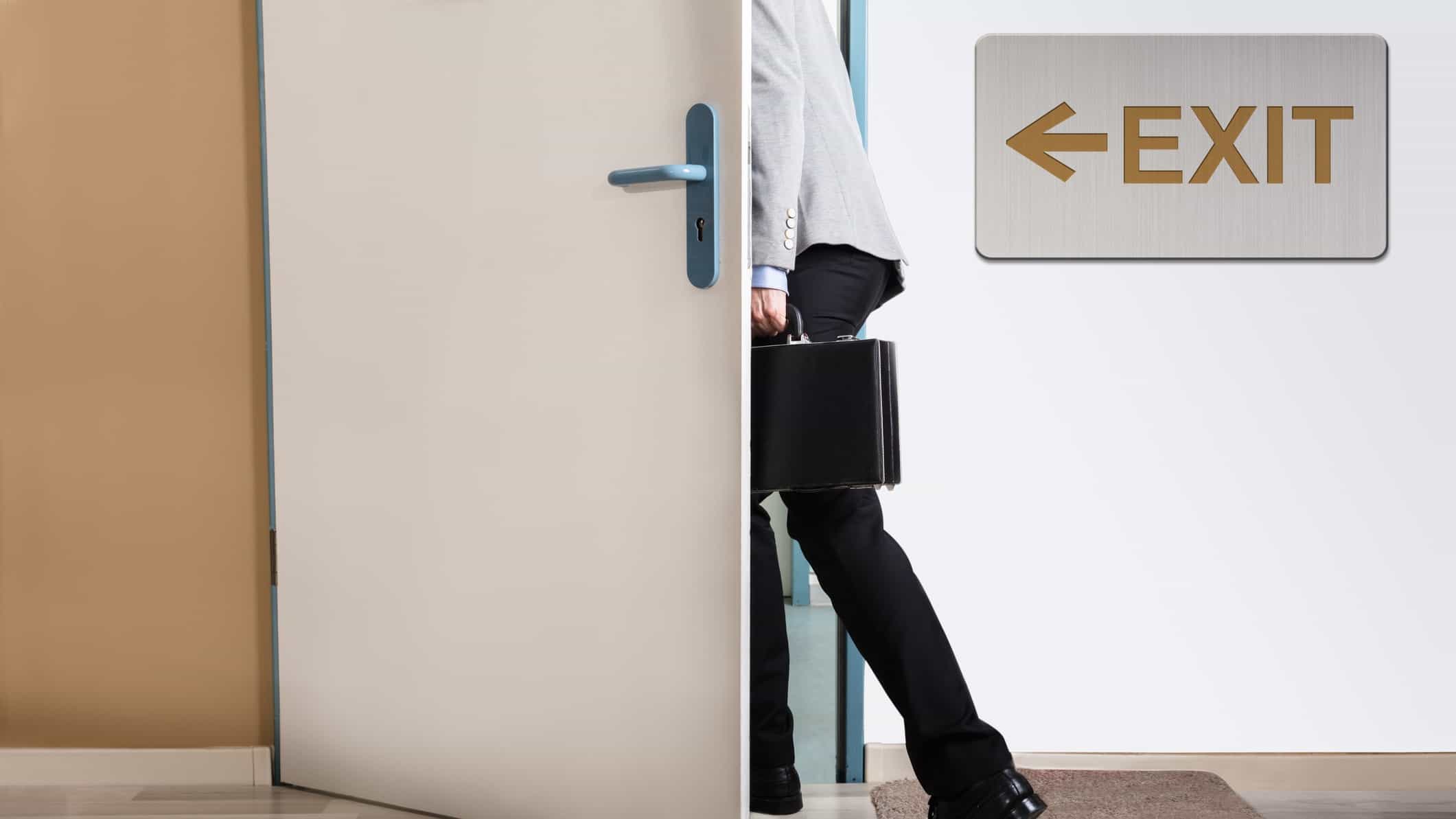 Businessman walks through exit door signalling resignation