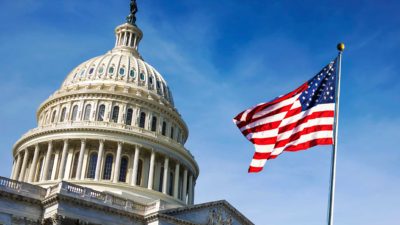 US flag and senate building with blue sky in background