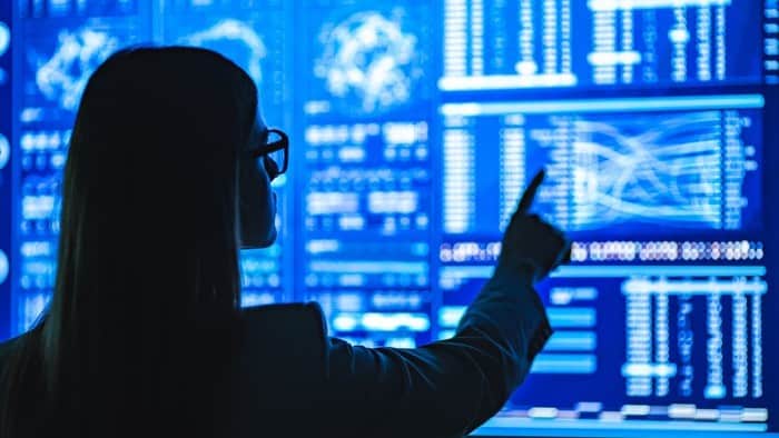 qoman standing in front of digital screen pointing