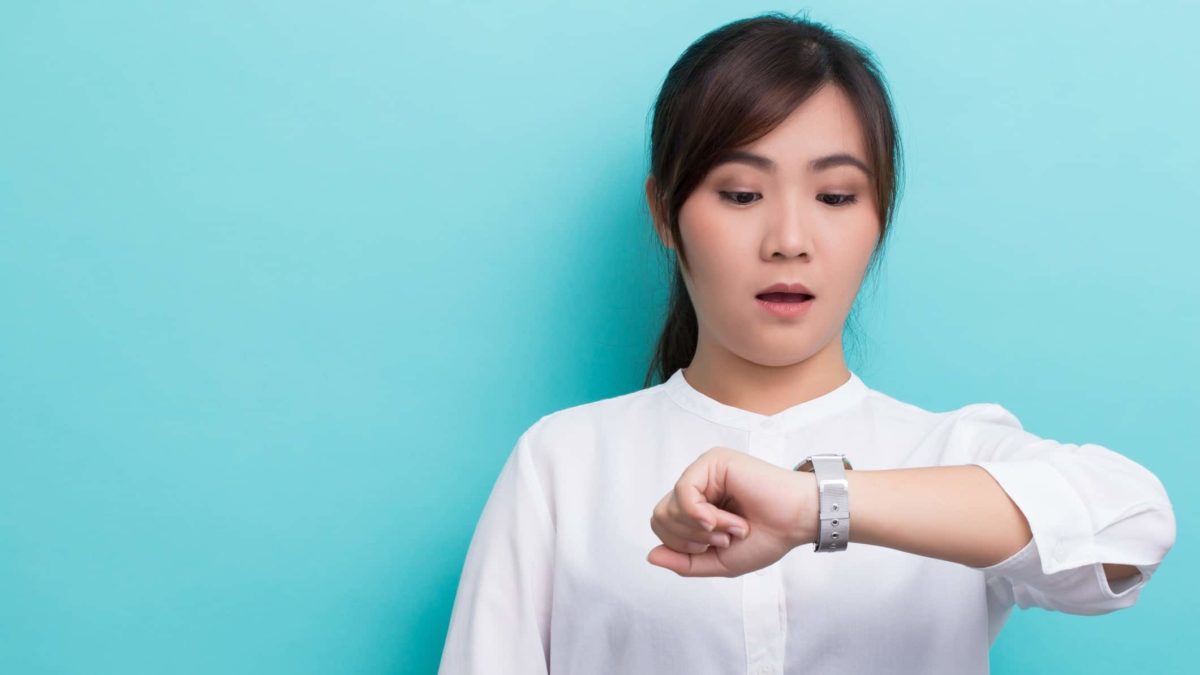 A woman looking at her watch representing need to buy ASX shares urgently.