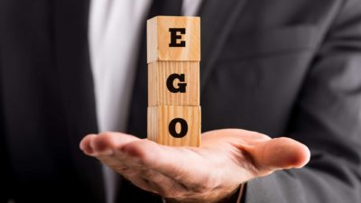 asx investor holdind wooden blocks in hand that spell ego
