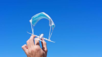 hand holding miniature plane suspended by face mask representing asx travel share price