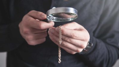 cash converters staff member examining gold bracelet under magnifying glass