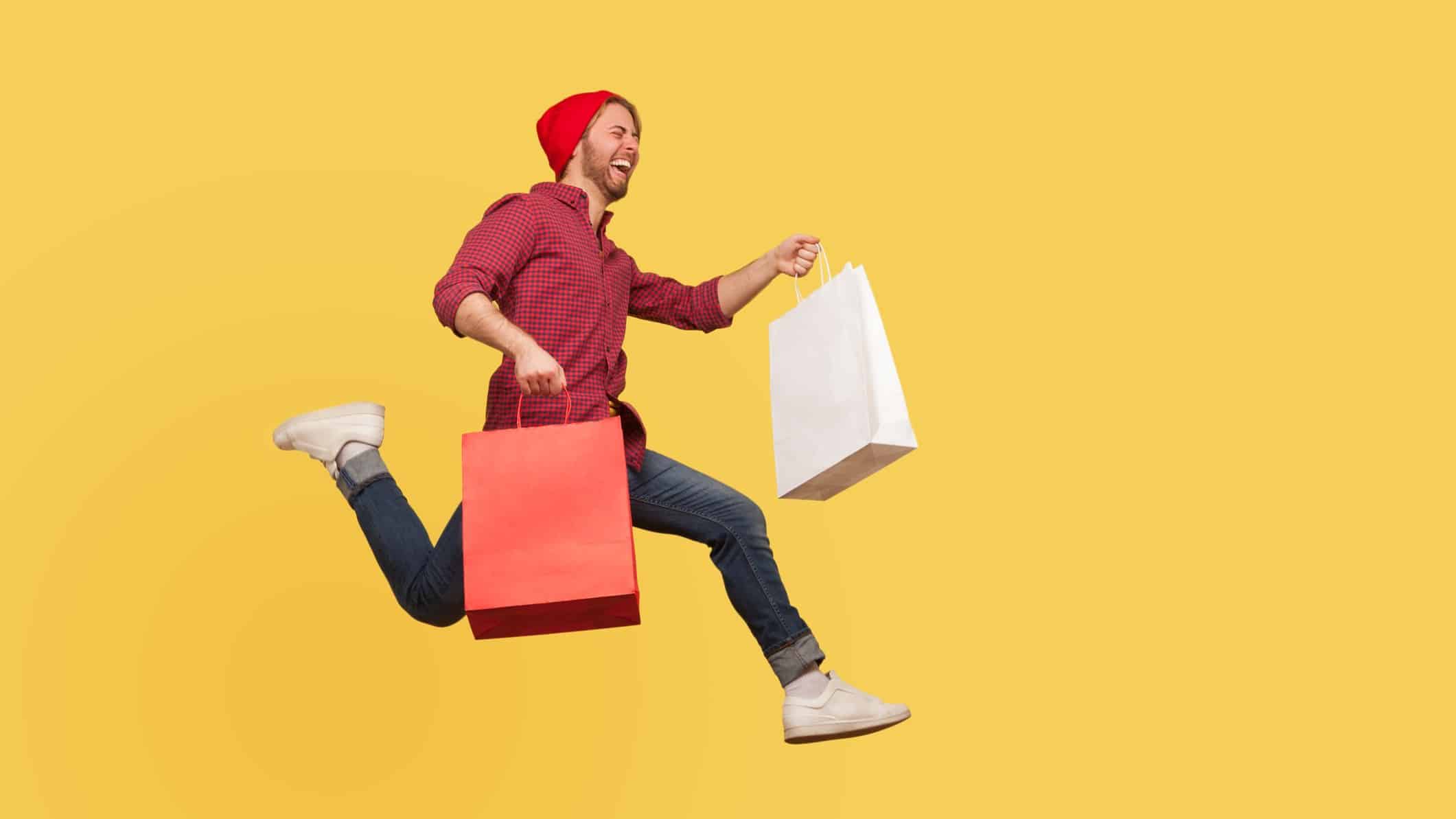 man jumping for joy carrying shopping bags