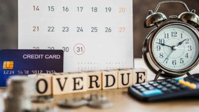 calendar with date circled, blocks spelling overdue, alarm clock, credit card and calculator