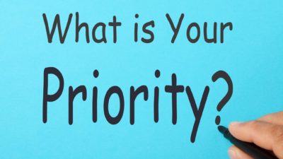 blue sign with black writing stating 'what is your priority?'