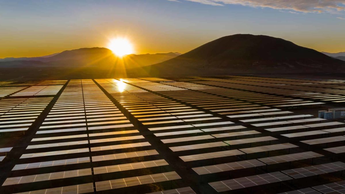 renewables fund solar energy farm with sun setting over mountain