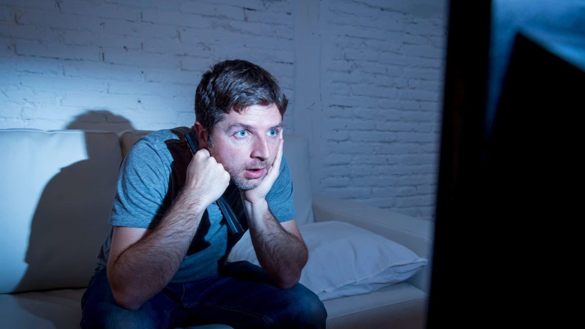 man intently watching tv representing media asx share price on watch