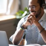Young male investor smiling looking at laptop as the share price of ASX ETF CRYP goes higher today