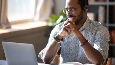 Young male investor smiling looking at laptop as the share price of ASX ETF CRYP goes higher today