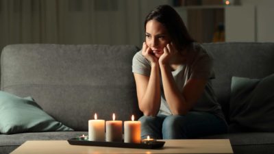 woman sitting glumly in the dark with candles