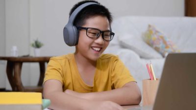 boy wearing headphones and doing online education in front of computer