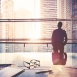 Silhouette of CEO standing in conference room looking out at cityscape.