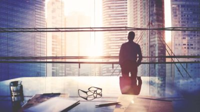 Silhouette of CEO standing in conference room looking out at cityscape