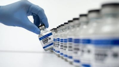 CSL share price represented by hand in blue glove picks out a vial labelled 'covid-19 vaccine' from a row of vials