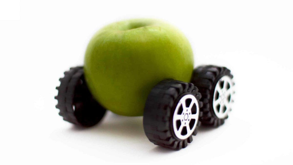 apple and tesla shares represented by image of an apple on wheels