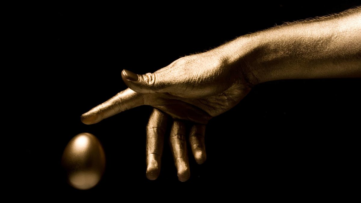hand covered in gold spray paint touching golden egg representing asx growth shares