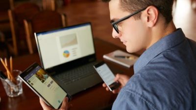 man looking at his phone and comparing investments