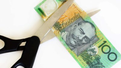 pair of scissors cutting one hundred dollar note representing cut dividend