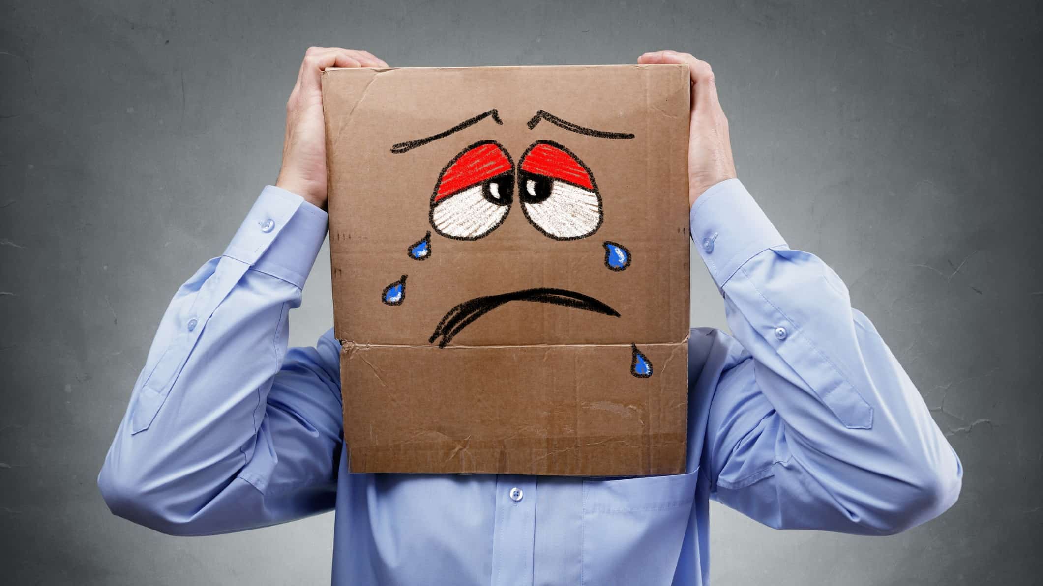 falling asx share price represented by business man wearing box on his head with a sad, crying face on it