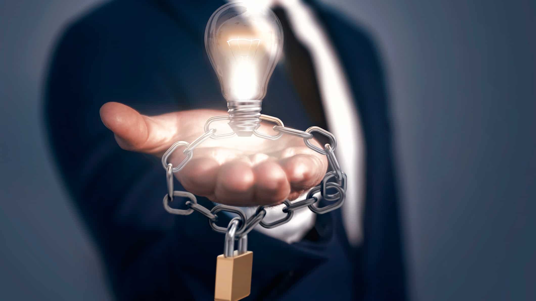 man holding a light bulb with a chain and padlock around it