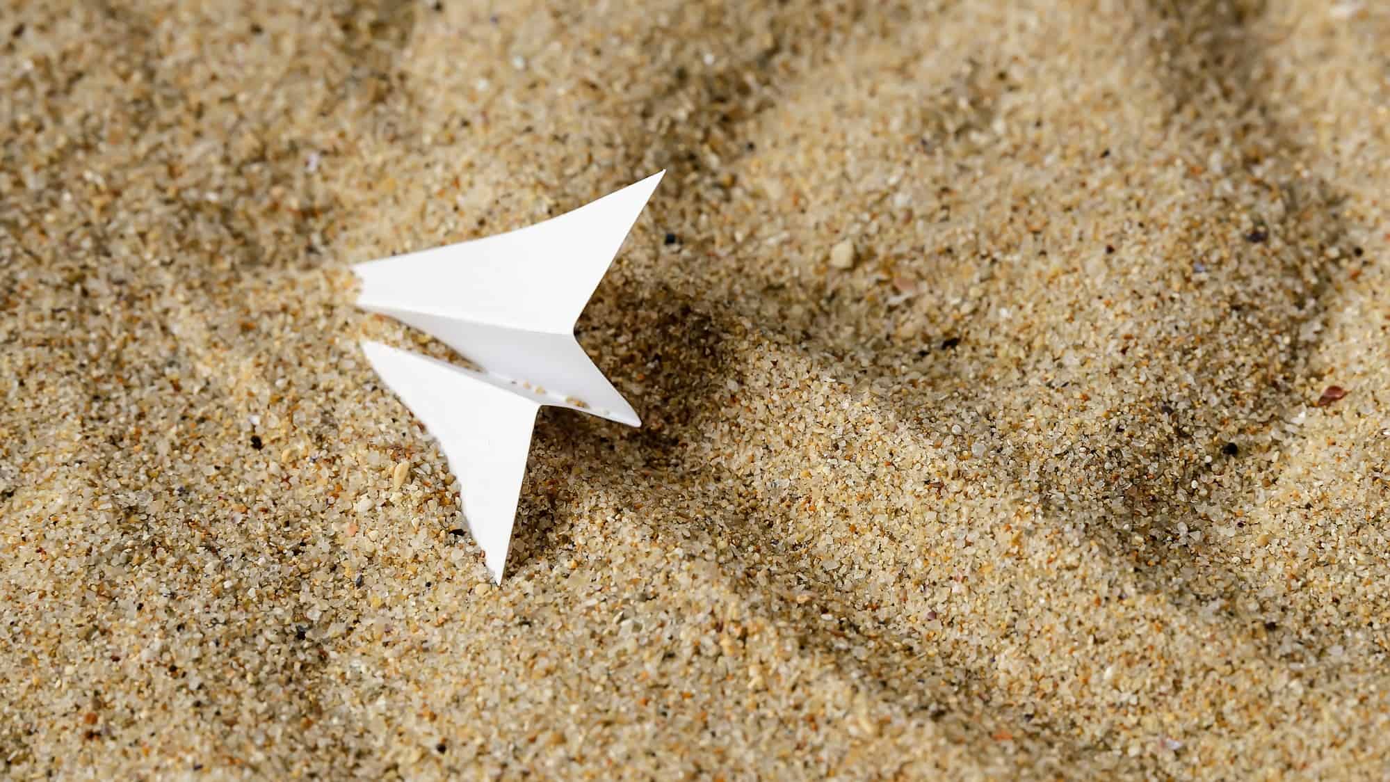 paper plane crashed in sand representing falling nearmap share price