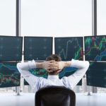Investor sitting in front of multiple screens watching share prices